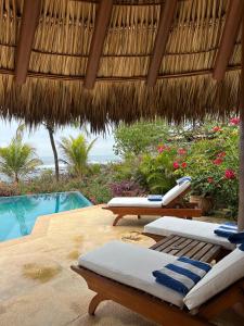 a pool with two lounge chairs and a straw umbrella at Casamar, beach front estate on Troncones Point in Troncones +14 photos