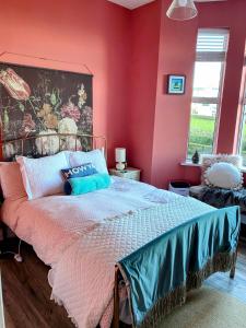 a bedroom with a large bed with pink walls at Port Pour Deux in Portrush