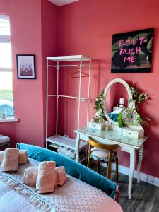 a bedroom with pink walls and a table and a bed at Port Pour Deux in Portrush