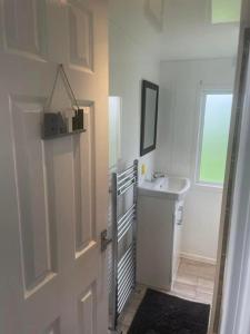 ein weißes Badezimmer mit einem Waschbecken und einer Tür in der Unterkunft bee-side the sea whitley bay in Hartley + 1 Foto