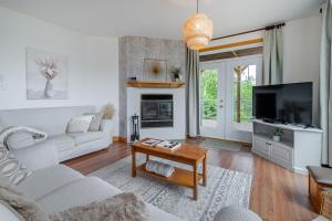 a living room with white furniture and a fireplace at 5 Chambres et 3 salles de bain avec Spa, vue, foyer et plus in Petite-Rivière-Saint-François
