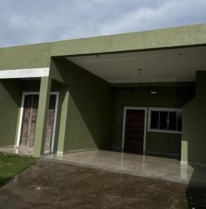 a green building with a door and a garage at Luciene in Xangri-lá