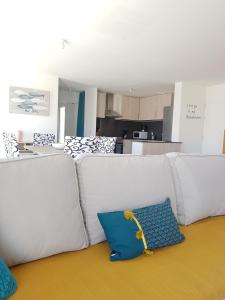 a living room with a white couch with a blue pillow at VIlla Elise, lumineuse et proche plage in LʼÉpine