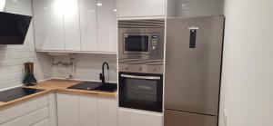 a kitchen with a stainless steel refrigerator and a microwave at Piso centrico in La Línea de la Concepción