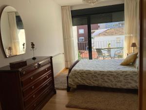 a bedroom with a bed and a dresser and a window at Apartamento completo y equipado a 3 minutos de la playa in Bueu