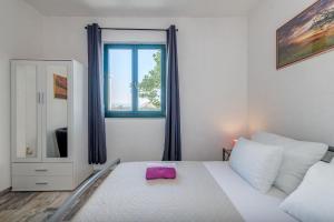 a bedroom with a white bed with a pink pillow at Apartments Deepwater in Slatine
