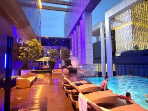 a pool in a hotel with chairs and people in it at Platinum KLCC Suites Face in Kuala Lumpur