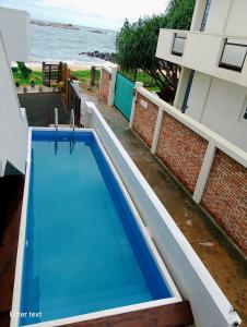 a blue swimming pool next to a building and the ocean at Hanka Villa -Ambalangoda in Ambalangoda