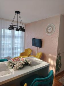 Vrnjačka BanjaにあるApartman Ljubičicaのリビングルーム(テーブル、黄色い椅子、時計付)