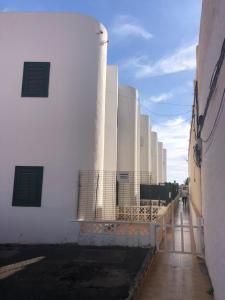 a white building with a fence next to it at Silent coast apartment in Las Galletas