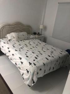 a bed with a white comforter with black birds on it at Silent coast apartment in Las Galletas
