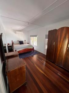 Un dormitorio con una cama y suelo de madera. en Beach side, air conditioned, 3 bedroom cottage, en Urangan