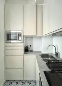 a white kitchen with a sink and a microwave at Studio de charme à Montrouge - 20 m² - Internet inclus in Montrouge