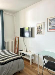 a bedroom with a bed and a desk and a tv on the wall at Studio de charme à Montrouge - 20 m² - Internet inclus in Montrouge