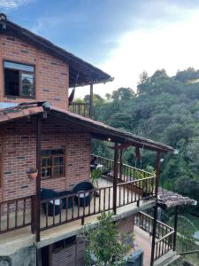una casa con una terraza con sillas. en Finca Acogedora con Área de BBQ, Parking Privado y Hamacas, en Guarne