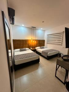 a bedroom with two beds and a tv in it at Hotel Merlott Lleras in Medellín