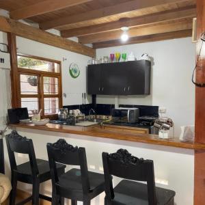 cocina con encimera con sillas y fogones en Finca Acogedora con Área de BBQ, Parking Privado y Hamacas, en Guarne