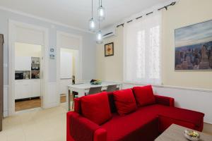 a living room with a red couch and a table at Casetta Fardella 95 in Trapani