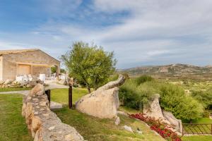 a house with a stone fence and some rocks at Moma Hotel Cannigione in Cannigione +32 photos