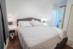 een bed met witte lakens en kussens in een slaapkamer bij APT Near Hospital,UofM,EMU in Ypsilanti