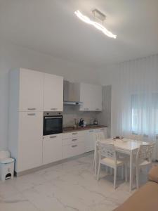 a kitchen with white cabinets and a table with chairs at Casa enna in Piacenza