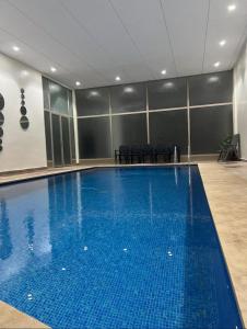 ein großer blauer Pool in einem Zimmer mit Stühlen in der Unterkunft Appartement luxe au cœur de Marrakech in Marrakesch