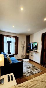 a living room with a blue couch and a flat screen tv at Cantinho do Auka - Studio in Aveiro