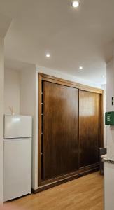 a kitchen with a refrigerator and a wooden door at Cantinho do Auka - Studio in Aveiro