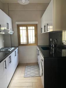 a kitchen with white cabinets and black counter tops at The view stay in Baabda +9 photos