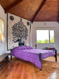 a bedroom with a purple bed and a tree mural at Casa Ganesha Lago Puelo in Lago Puelo
