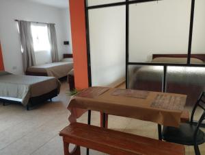 a room with two beds and a table and benches at CARRERO Departamentos Apart in Chepes