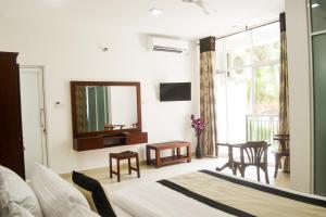 um quarto com uma cama, um espelho e uma mesa em Villa Ocean Dew - Beach Front em Galle