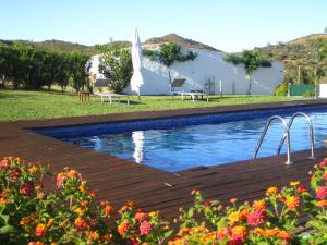 a swimming pool with a table and a white building at Casa da Osga in Tavira