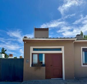 a house with a red door and a fence at El Garaje in Puerto Deseado