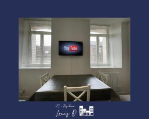 Zimmer mit einem Wand-TV und einem Tisch in der Unterkunft 2 Le Nid Bleu Béthunois Cosy and Central in Béthune