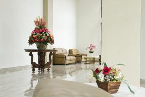 a lobby with two chairs and a table with flowers at Hotel Sepanak by Amazing in Curup