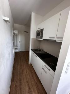 Una pequeña cocina con gabinetes blancos y un fregadero. en Appartement superbe, en Núremberg