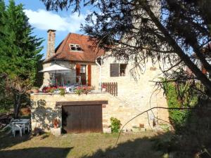 a stone house with a garage and an umbrella at Maison charmante à Lavercantière avec piscine partagée in Lavercantière