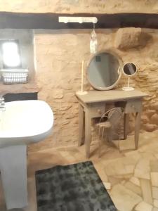 a bathroom with a vanity and a mirror on a stone wall at Maison charmante à Lavercantière avec piscine partagée in Lavercantière +13 photos