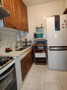 a kitchen with a white refrigerator and a sink at Apto 2 quartos em Capivari - Campos do Jordão in Campos do Jordão