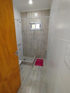a bathroom with a shower with a red rug at Cabañas del monte in Monte Hermoso