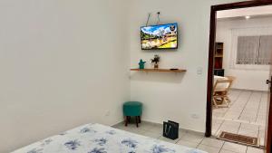 a bedroom with a bed and a tv on the wall at Kitnet nas Montanhas in Campos do Jordão