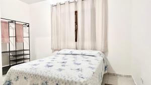 a bed in a white room with a window at Kitnet nas Montanhas in Campos do Jordão
