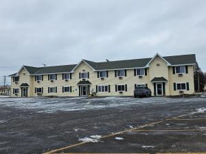a large white building with a car parked in a parking lot at Lincoln Host Motor Inn in Escanaba