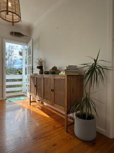 a room with a wooden cabinet and a potted plant at Manaia - A little bach near the beach in Moruya Heads