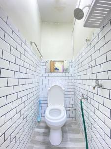 a bathroom with a toilet in a white tiled wall at Homestay Tanjung Malim DMalim in TanjongMalim +5 photos