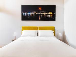 a bedroom with a white bed with a yellow headboard at Apartment near Mount Etna with Pool in Giarre