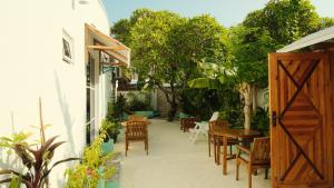a patio with a wooden door and chairs and trees at Faana Inn in Fulhadhoo