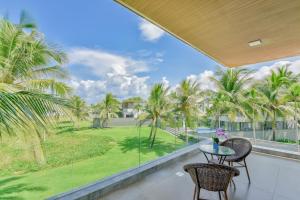 a balcony with a table and chairs and palm trees at The Five Stars Villa 7 Bedrooms Beachfront in Danang