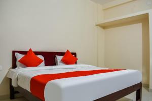 a bedroom with a bed with red pillows at Super Hotel O Shiv Sai Palace in Bhubaneshwar